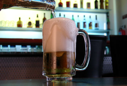 A beer with suds flowing over the glass