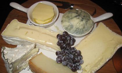 A selection of hard and soft cheeses with grapes
