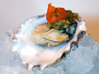 A fresh oyster on a bed of ice topped with sauce