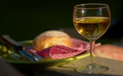 A glass of white wine with a dinner roll